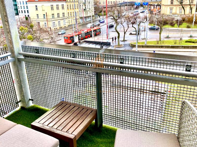 Balkon s posezením a výhledem na tramvaj na ulici v Bratislavě - Starém Městě.