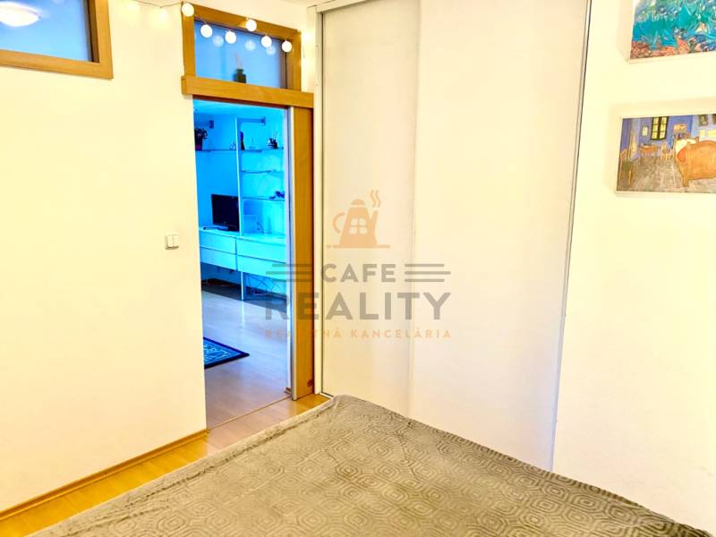 Interiér 2-pokojového bytu s posuvnými dveřmi a podlahou s dřevěným dekorem.