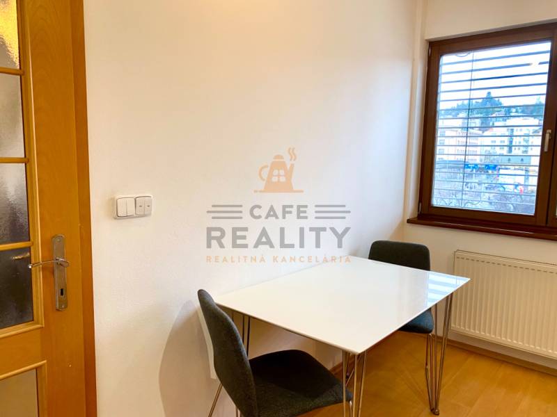 Jídelní kout s bílým stolem a židlemi v 2pokojovém bytě, podlaha s dřevěným dekorem.