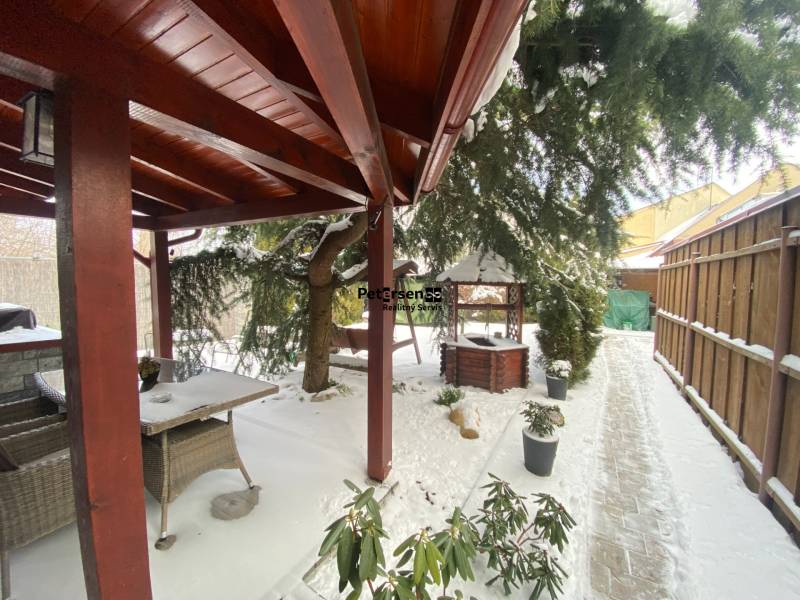 Zasněžená terasa u rodinného domu na Rampové ulici v Košicích s altánkem a zelení.