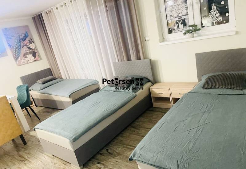 Tři postele, dva noční stolky a podlaha s dřevěným dekorem v rodinném domě.