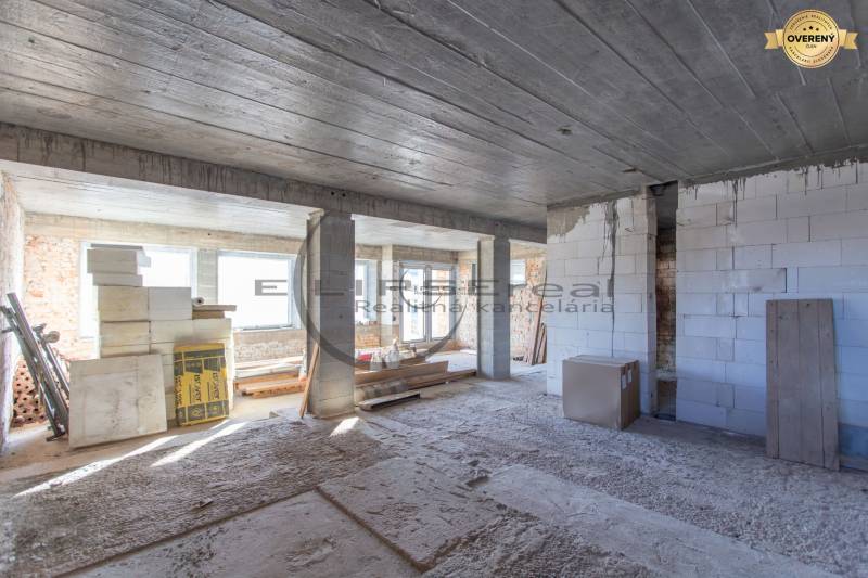 Interiér budovy ve výstavbě se stavebním materiálem a betonovým stropem.