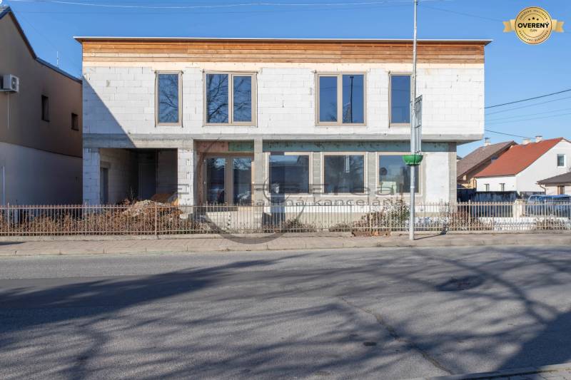 Budova ve Velkých Levárech s nedokončenou fasádou stojící u cesty.