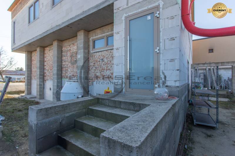 Budova ve Velkých Levárech s nedokončenou fasádou a schody na betonovém základu.