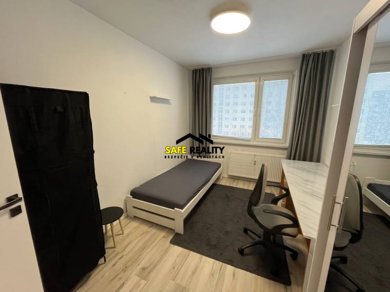 Ložnice ve 3-pokojovém bytě s postelí, stolem a podlahou s dřevěným dekorem.