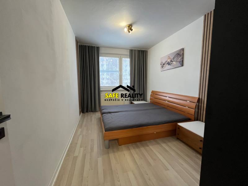 Ložnice se světlými stěnami, manželskou postelí a podlahou s dřevěným dekorem ve 3pokojovém bytě.