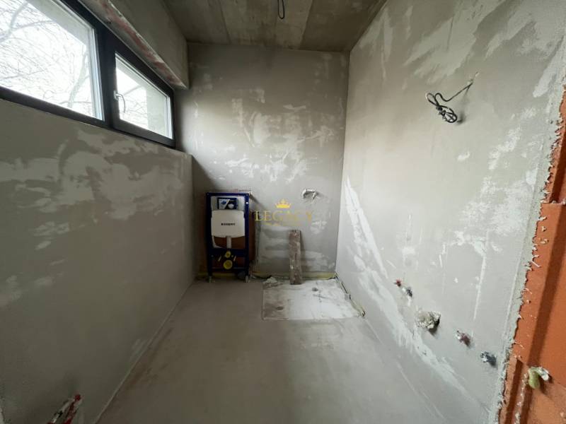 Nedokončená koupelna v rodinném domě s výhledem přes okno.