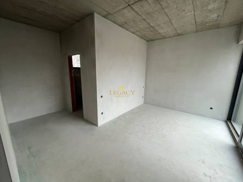 Interiér s betonovým stropem a okny v rodinném domě, připravený k dokončení.