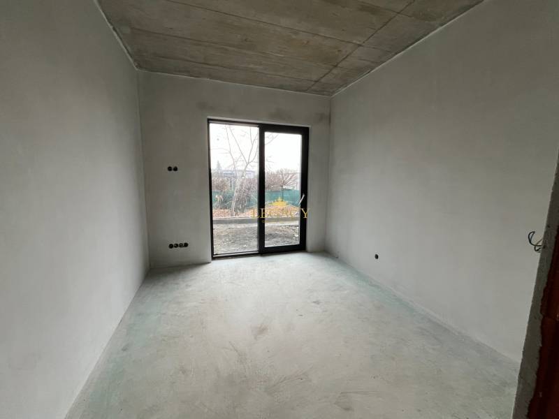 Prázdná místnost s betonovou podlahou a velkými okny v rodinném domě.