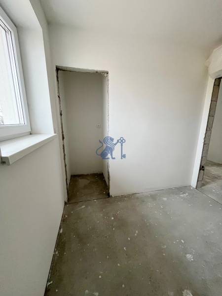 Pokoj v 3-pokojovém bytě s oknem, omítnuté stěny, betonová podlaha, stavební úpravy.