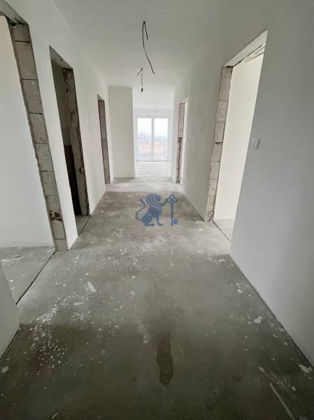 Interiér rozestavěného 3-pokojového bytu s prázdnou chodbou a základem podlahy.