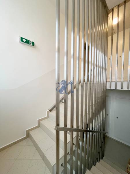 Schodiště se zábradlím a únikovou značkou ve 2-pokojovém bytě.