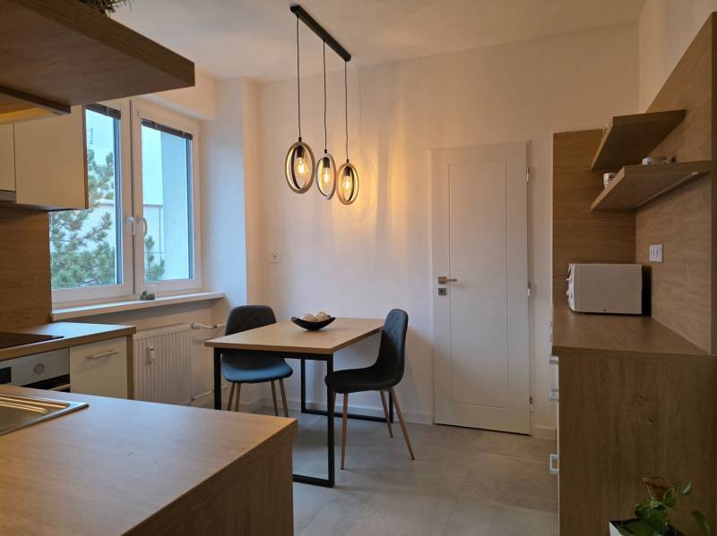 Kuchyně ve 3-pokojovém bytě s podlahou s dřevěným dekorem a závěsnými svítidly.