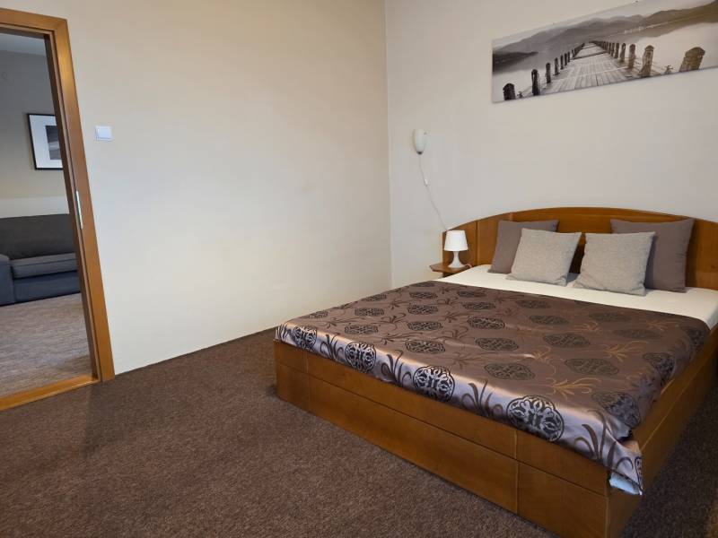 Ložnice v 3-pokojovém bytě se stylovou postelí, zářivým povlečením a příjemným kobercem.