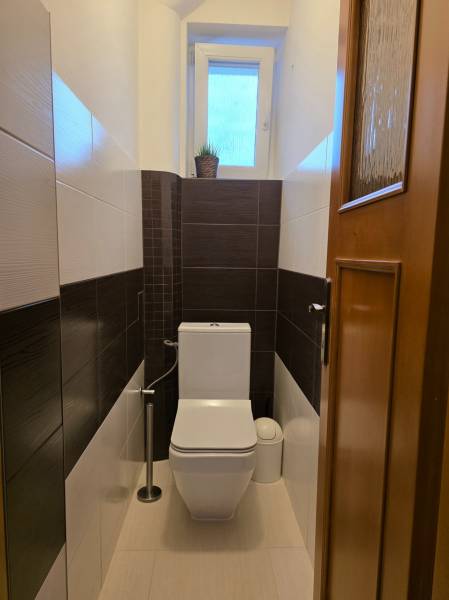 Útulná toaleta se světlými stěnami a oknem v 3-pokojovém bytě.