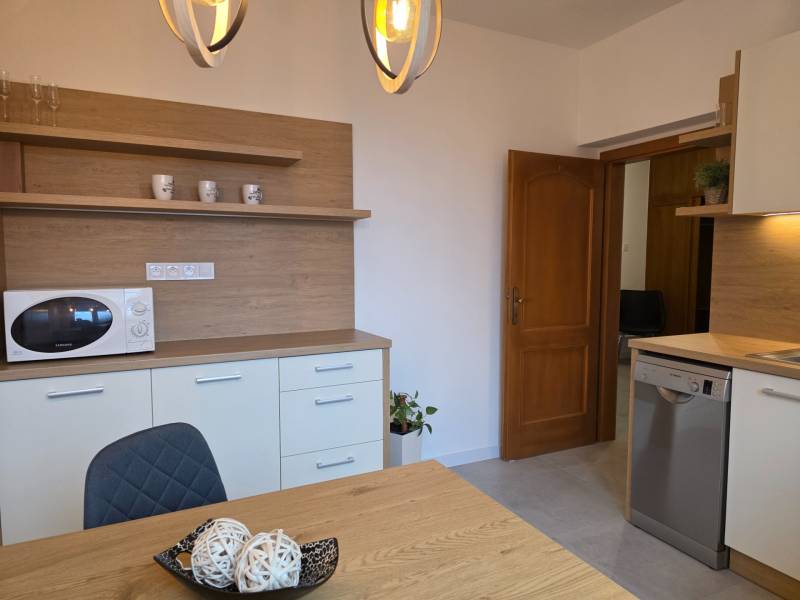 Kuchyně se stolem a židlí ve 3-pokojovém bytě, s dřevěným dekorem a mikrovlnkou.