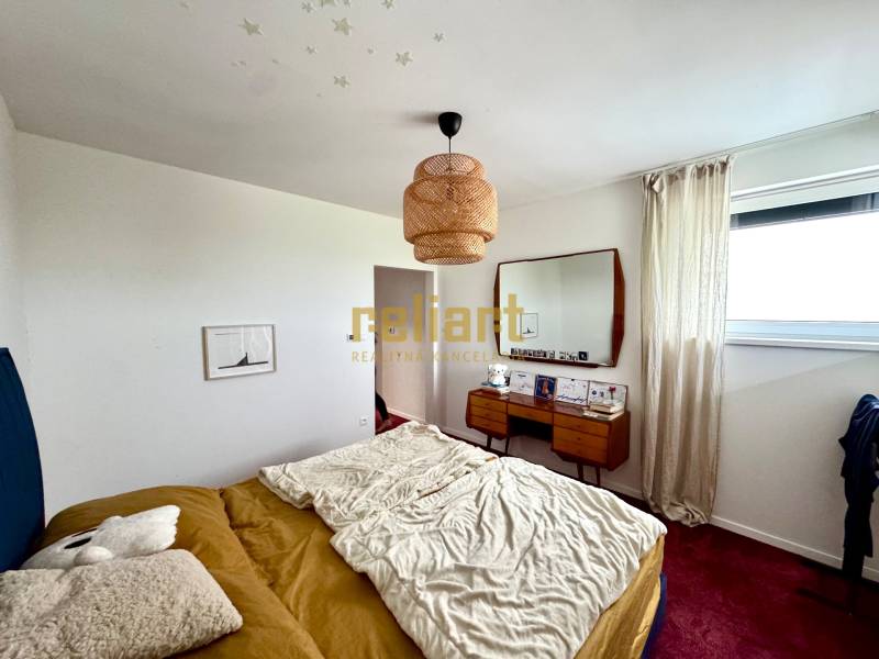 Ložnice v rodinném domě s postelí, zrcadlem a červeným kobercem na podlaze.