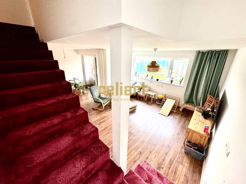 Interiér rodinného domu se schodištěm a obývacím pokojem s podlahou s dřevěným dekorem.