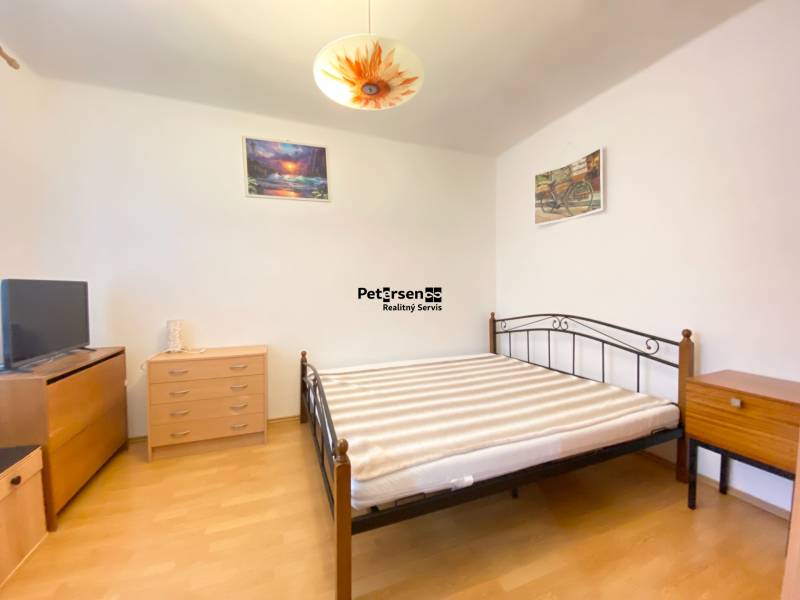 Ložnice v 2pokojovém bytě s nábytkem a podlahou s dřevěným dekorem.