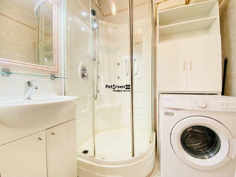 Koupelna v 2-pokojovém bytě s pračkou, sprchovým koutem a umyvadlem.