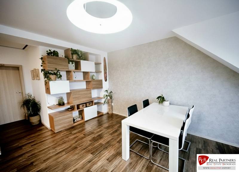 Jídelní stůl, židle a police s dekoračními prvky v 3-pokojovém bytě s podlahou s dřevěným dekorem.