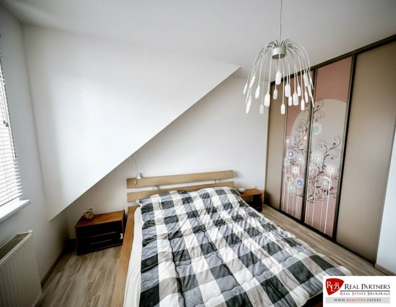 Ložnice v 3-pokojovém bytě s postelí, vestavěnou skříní a podlahou s dřevěným dekorem.