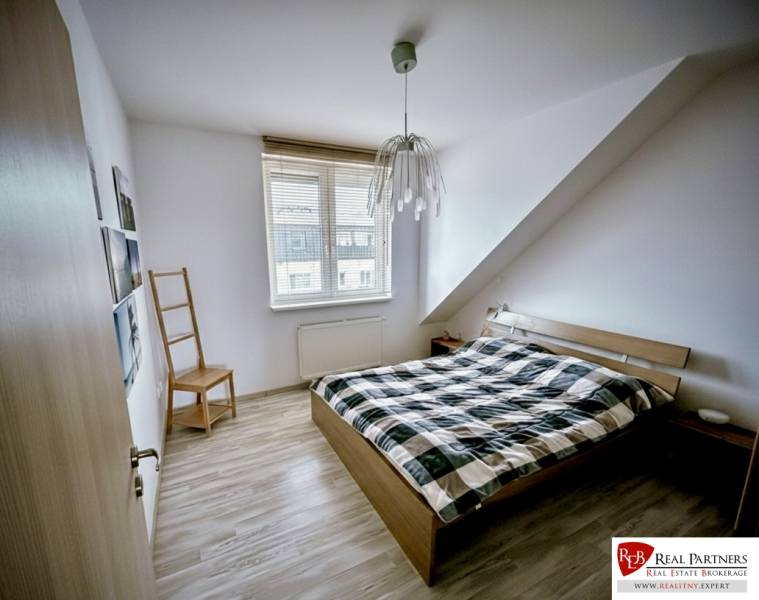 Ložnice v 3-pokojovém bytě s postelí a podlahou s dřevěným dekorem.