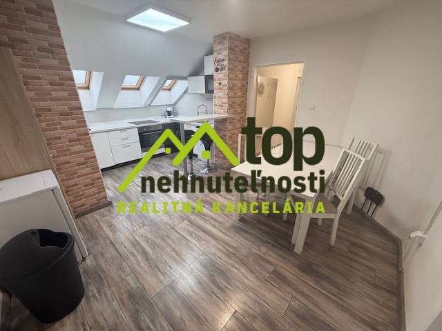 Interiér 1-pokojového bytu s podlahou s dřevěným dekorem a kuchyní s cihlovým obložením.