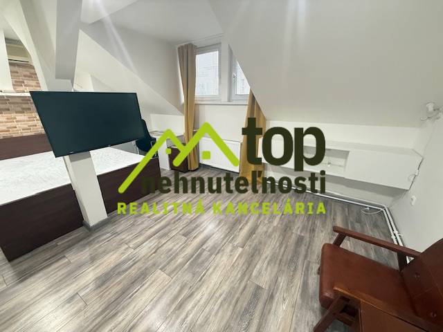 Pokoj s podlahou s dřevěným dekorem, moderní televize a nábytek v 1-pokojovém bytě.