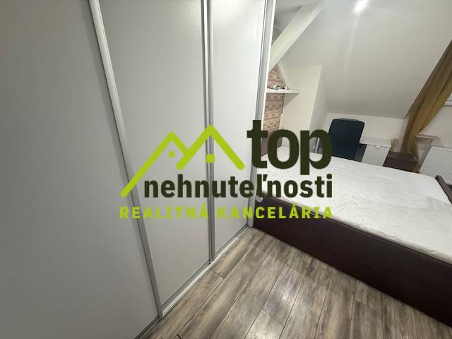 Ložnice v jednopokojovém bytě s podlahou s dřevěným dekorem a vestavěnou skříní.