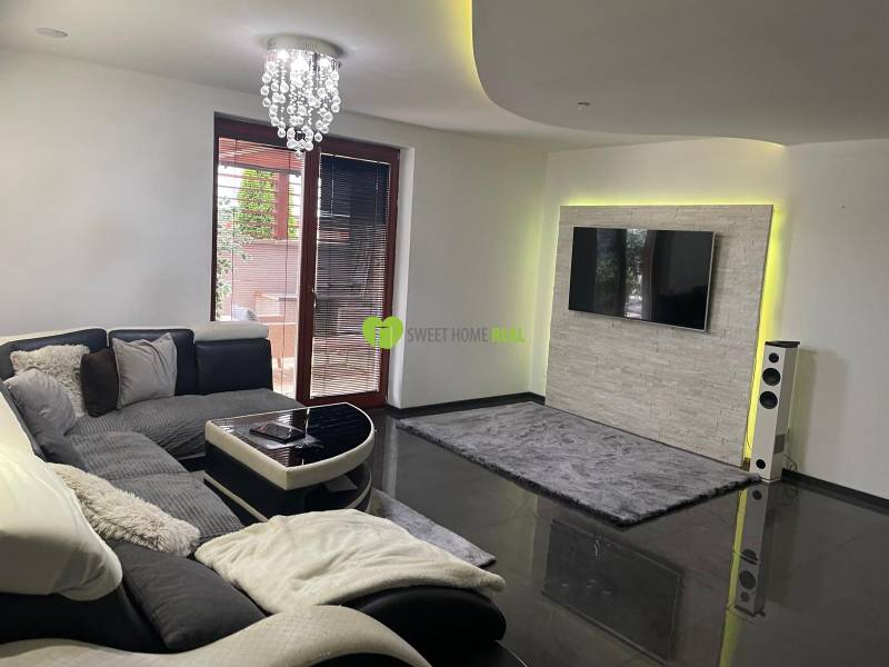 Obývací pokoj v rodinném domě s pohovkou a televizorem na stěně s kamenným obkladem.