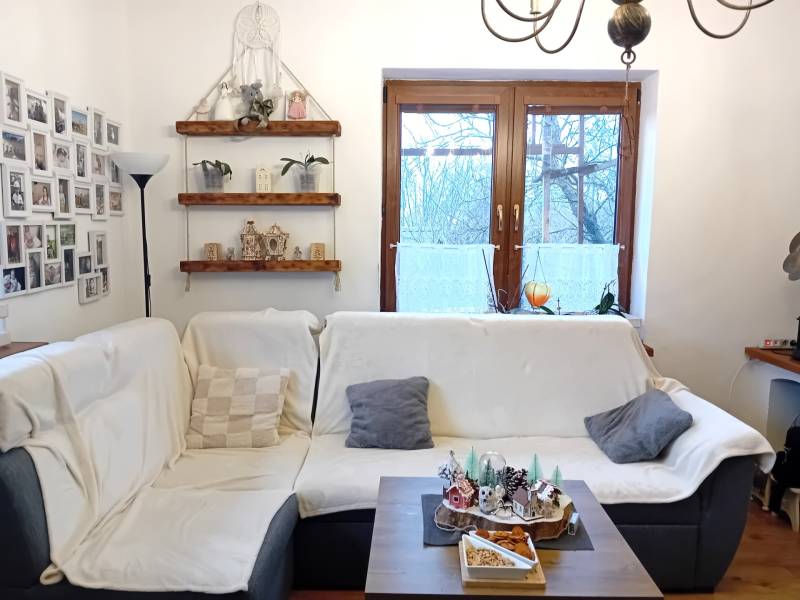 Obývací pokoj v rodinném domě s pohovkou, fotogalerií, policemi a dekoracemi.