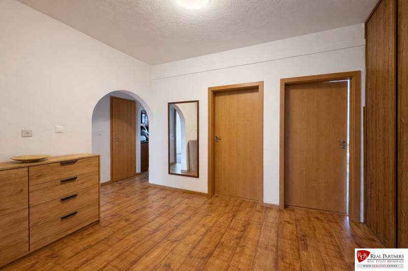 Chodba s podlahou s dřevěným dekorem a dřevěnými dveřmi ve 4pokojovém bytě.