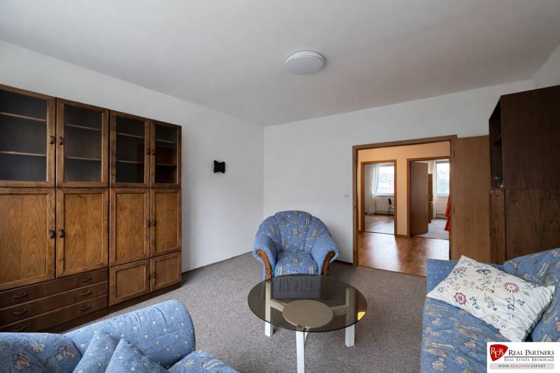 Obývací pokoj s pohovkou, skříní a stolkem ve 4pokojovém bytě.