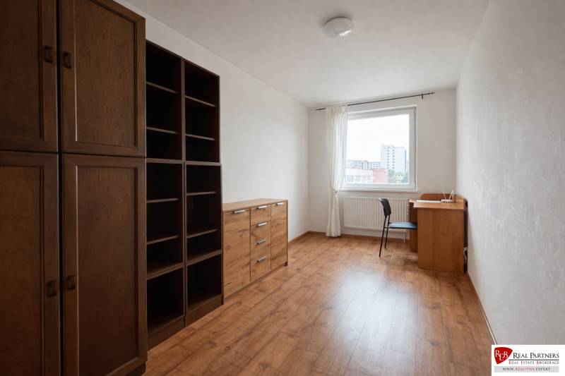 Pokoj ve 4pokojovém bytě s podlahou s dřevěným dekorem a nábytkem z tmavého dřeva.