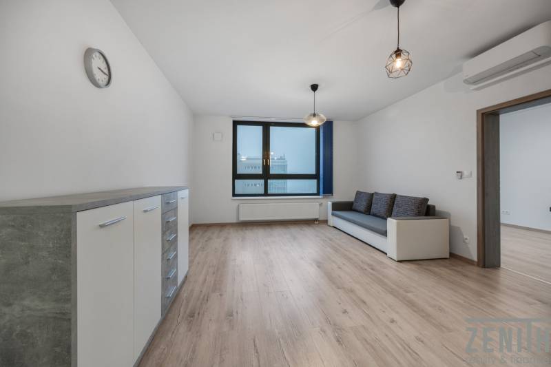 Obývací pokoj v 2-pokojovém bytě s pohovkou a podlahou s dřevěným dekorem.