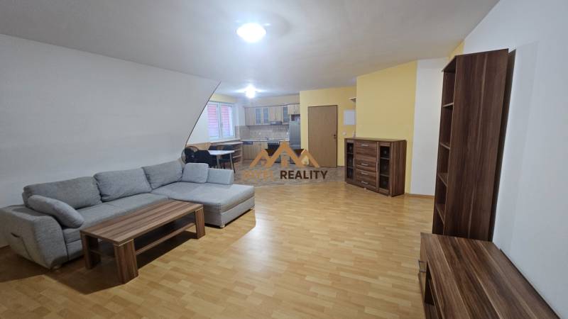 Obývací pokoj s pohovkou, kuchyní a podlahou s dřevěným dekorem ve 3pokojovém bytě.