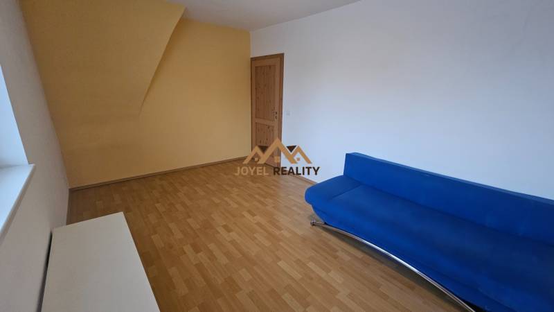 Obývací pokoj v 3-pokojovém bytě s podlahou s dřevěným dekorem a modrou pohovkou.