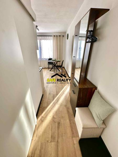 Světlý interiér s jídelním stolem a podlahou s dřevěným dekorem v 1-pokojovém bytě.