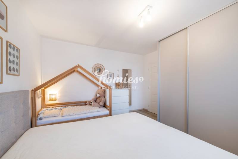 Dětský pokoj v dvoupokojovém bytě s dětskou postelí a skříní.