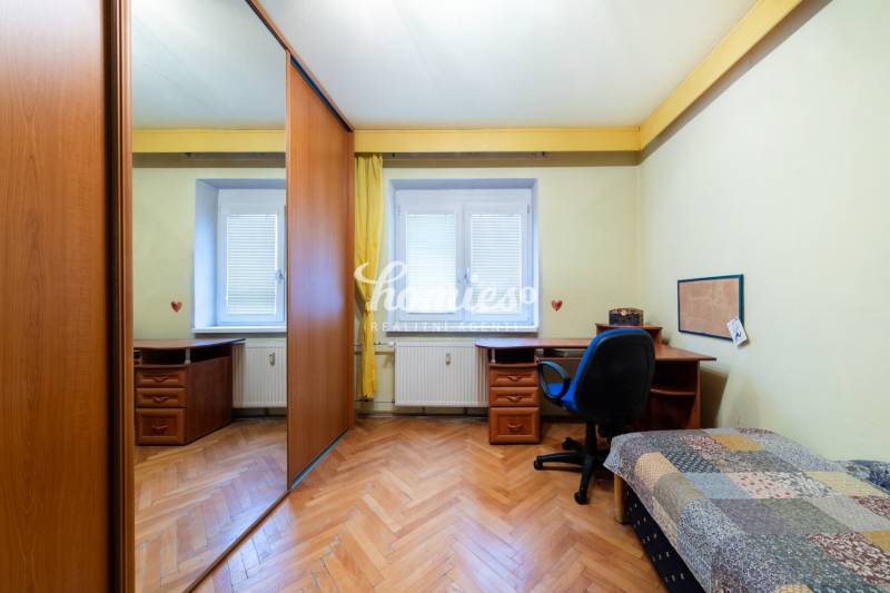 Pokoj s podlahou s dřevěným dekorem, stolem a skříní ve 3-pokojovém bytě.