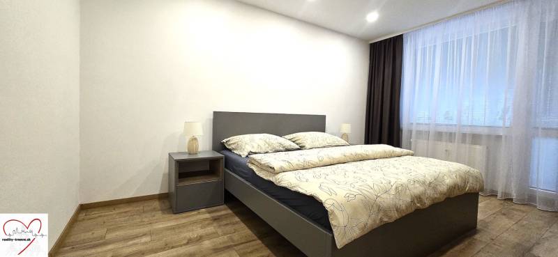 Ložnice s postelí, nočním stolkem a podlahou s dřevěným dekorem ve 3-pokojovém bytě.