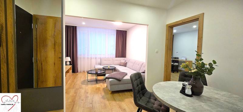 Obývací pokoj 3pokojového bytu s pohovkou, stolkem a podlahou s dřevěným dekorem.