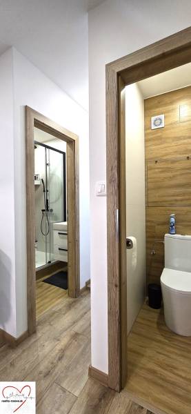 Chodba s podlahou s dřevěným dekorem, dvě místnosti, koupelna a toaleta ve 3-pokojovém bytě.