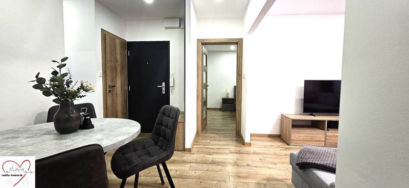 Interiér 3-pokojového bytu s podlahou s dřevěným dekorem a stylovým stolem.