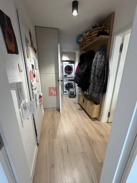 Úzká chodba se skříněmi a podlahou s dřevěným dekorem ve 4-pokojovém bytě.