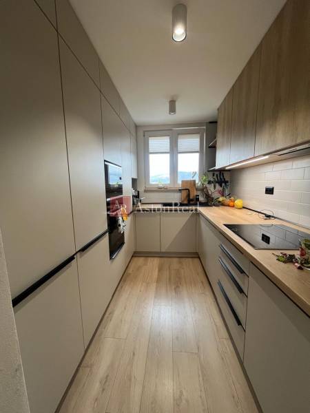 Kuchyně ve 4-pokojovém bytě s podlahou s dřevěným dekorem, světlé skříňky, okno.