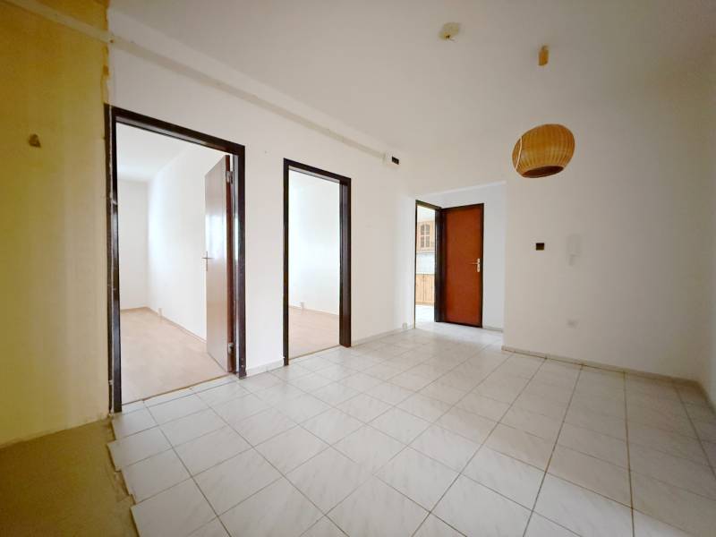 Interiér 4-pokojového bytu s bílými stěnami, dlažbou a podlahou s dřevěným dekorem.