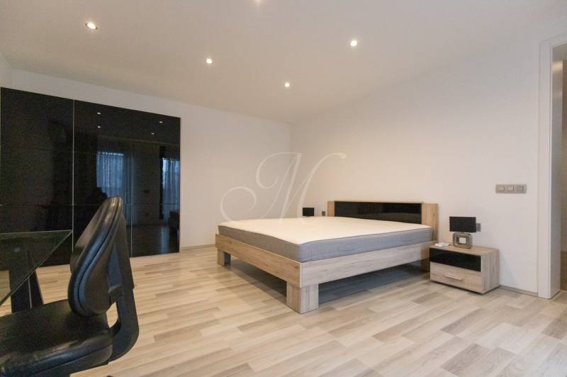 2pokojový byt s podlahou s dřevěným dekorem, postelí, skříní a kancelářskou židlí.