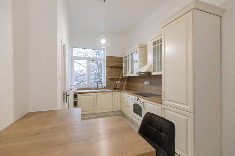 Kuchyně v 3-pokojovém bytě s podlahou s dřevěným dekorem a klasickými kuchyňskými skříňkami.